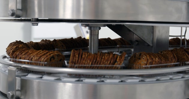 Mondēlez's expansion and upgrade at its Gourmet Foods cracker manufacturing facility includes automated pick and place robots with the crackers going into trays.