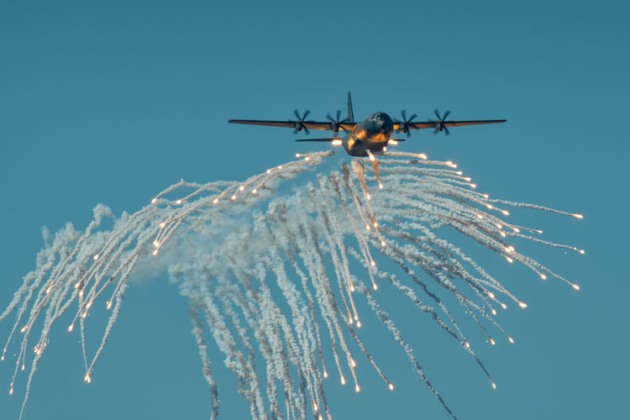 Despite the bright sunlight, flares paint a golden light across this RAAF Hercules. (John Absolon)