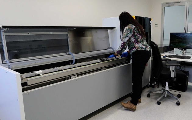 Patricia Gadd, part of the collaborative team, handles an organic sample using the full-sized itrax scanner in the lab. Image: ANSTO.