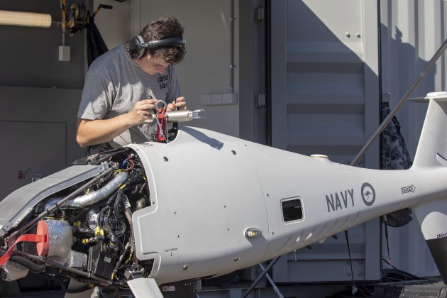 A technician inspecting the main rotor assembly on the Schiebel S-100 Camcopter prior to a flight from Jervis Bay airfield.
Defence