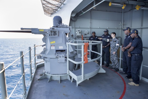 Able Seaman Jacob Haines shows members from the Vanuatu Police Force Maritime Wing a Typhoon gun during a guided tour of HMAS Adelaide. 
Defence