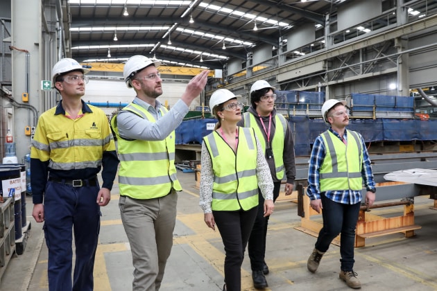 Scholarship recipients Jackson Preus, Andrew Penny, Alec Rusanoff, Kane O&rsquo;Brien, with Margot Forster (centre, DTC) taken at the Osborne Naval Shipyard OPV construction site. Credit: ASC