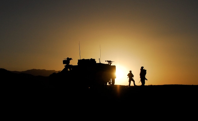 Australian soldiers and a Bushmaster Protected Mobility Vehicle are silhouetted against an Afghan sunrise as they prepared for another day's mission in a photo from 2009. Credit: Defence