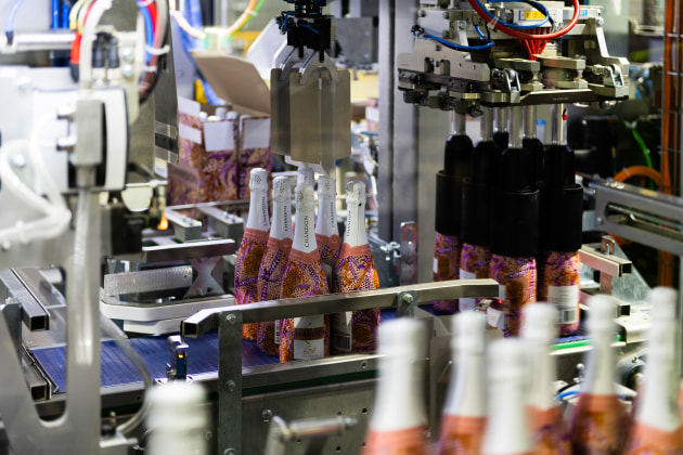 The picking head grabs and transfers bottles six at a time onto the automated partition inserter module.