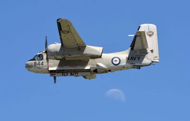 A Grumman Tracker sails past the crowdline as the moon looks on. (Steve Hitchen)
