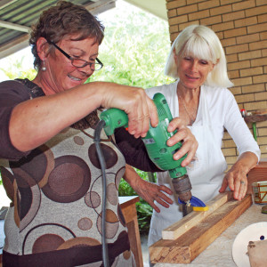 Patt Gregory (right) watches as a student learns power tool basics at one of her woodworking classes.